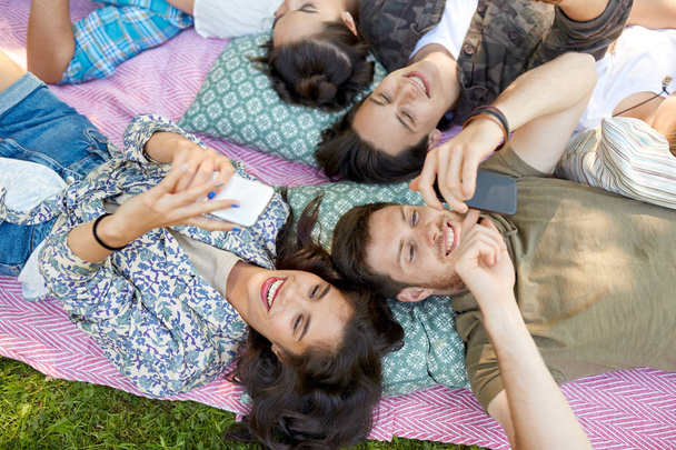 amigos con smartphones escalofriantes en el parque de verano
 - Foto, Imagen