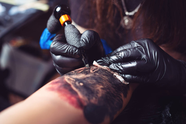 Tattoo artist makes a tattoo on a man's hand - Фото, зображення