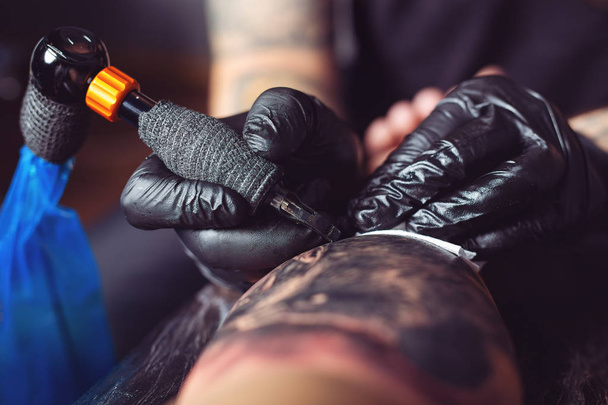 Tattoo artist makes a tattoo on a man's hand - Foto, Imagem