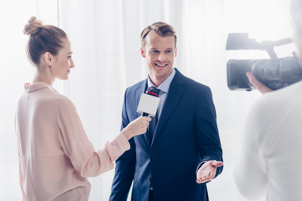 smiling handsome businessman giving video interview to journalist in office - Foto, imagen