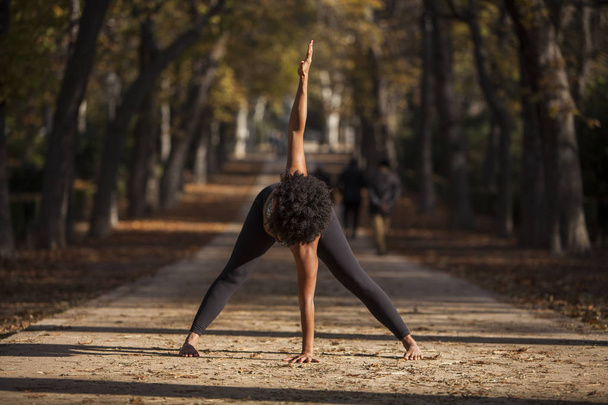 Belle femme afro pratiquant le yoga à l'extérieur, sur un chemin de parc
 - Photo, image