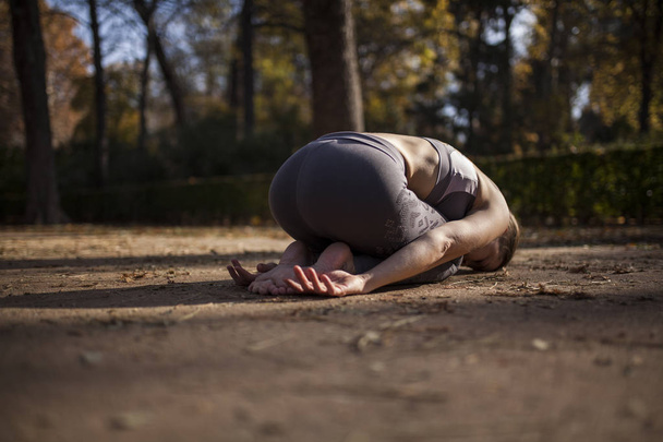 Mooie Kaukasische vrouw beoefenen van yoga, buitenshuis, park padtekst - Foto, afbeelding