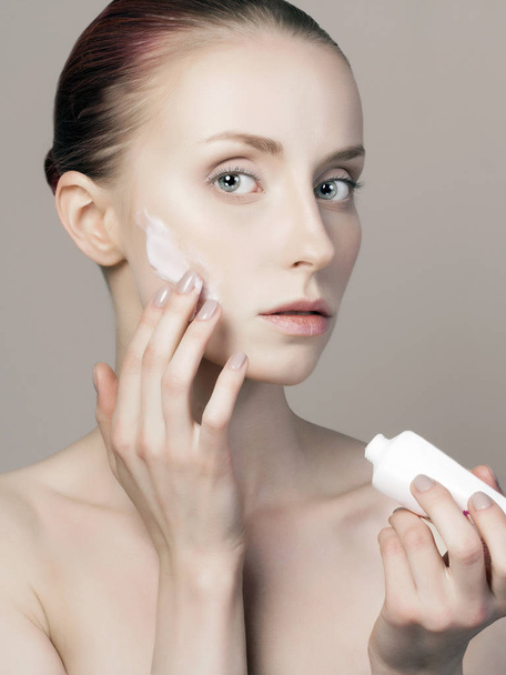young woman cares for face skin. beautiful girl with cosmetic cream on face. perfect Skin care concept - Foto, afbeelding