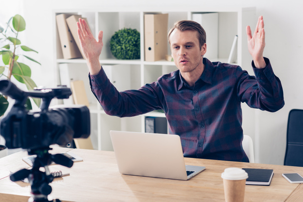 красивый видео-блогер в фиолетовой рубашке записывает видеоблог и жесты в офисе
 - Фото, изображение