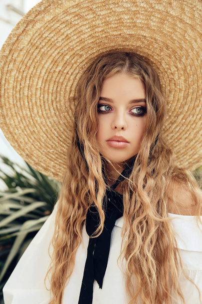 fashion outdoor photo of beautiful young baby face look girl with long curly hair wears elegant straw hat and blouse - Фото, изображение