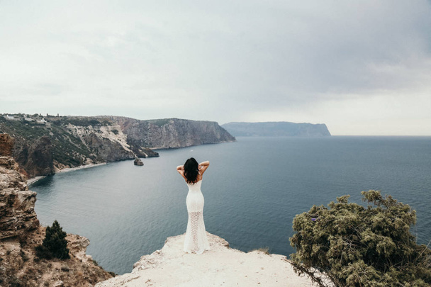 fashion outdoor photo of gorgeous bride in elegant wedding dress posing in the beautiful nature place, sea and mountains are on background - Zdjęcie, obraz
