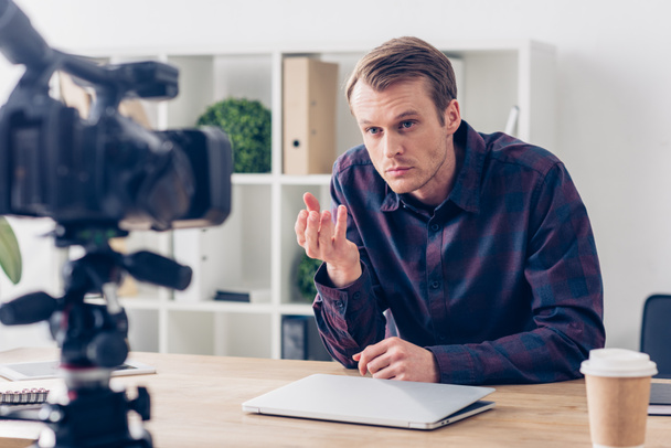 irritierte männliche Video-Bloggerin nimmt Vlog auf und gestikuliert im Büro - Foto, Bild