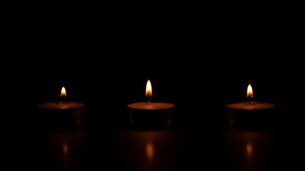 Trois bougies de cire allumées sur fond noir
. - Photo, image