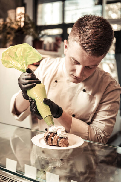 Nice young man finishing a croissant preparation - Фото, зображення