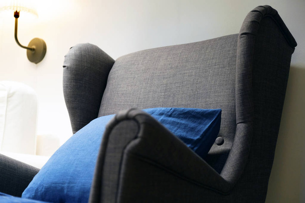 Blue soft chair with pillow, high back reading lamp above the head. Living room interior. - Fotó, kép