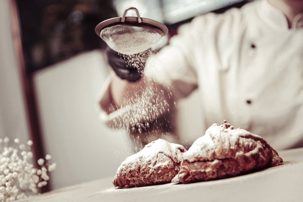 Sugar powder being put on two croissants - Photo, image