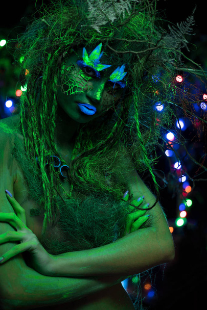 Mystic green dryad in UV fluor black light with Glowing trees on background - Foto, afbeelding