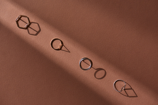 top view of beautiful luxury golden rings on brown surface with sunlight - Photo, image