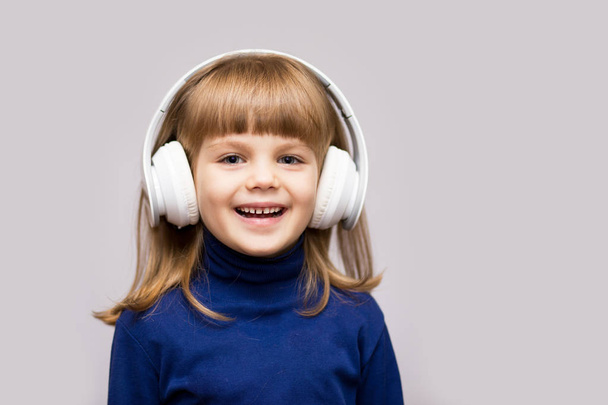 Счастливый улыбчивый ребенок наслаждается музыкой в наушниках на белом фоне
 - Фото, изображение