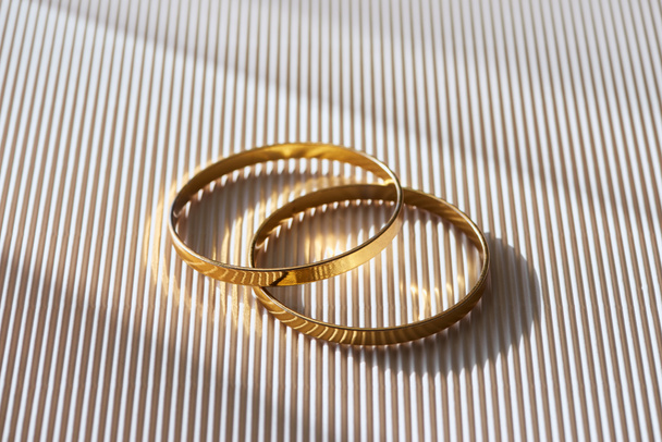 close up of beautiful luxury wedding rings on striped white surface with sunlight - Zdjęcie, obraz