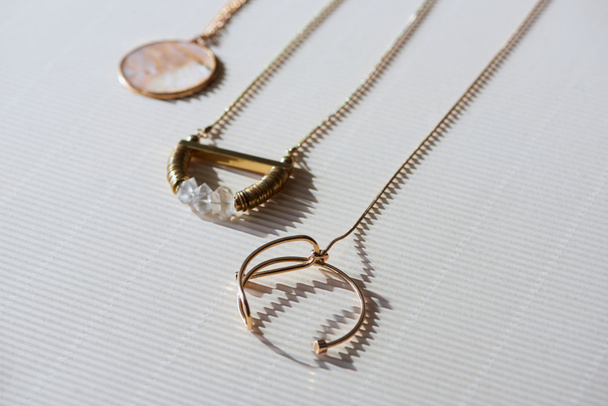 close up of beautiful luxury necklaces and round locket with marble on striped white surface with sunlight - Photo, Image