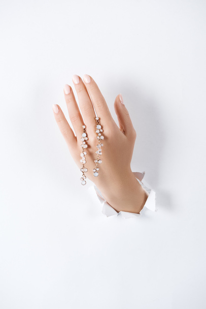 cropped image of woman holding hand with beautiful bracelet with diamonds through white paper - Фото, изображение