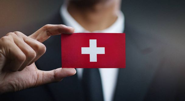 Businessman Holding Card of Switzerland Flag  - 写真・画像