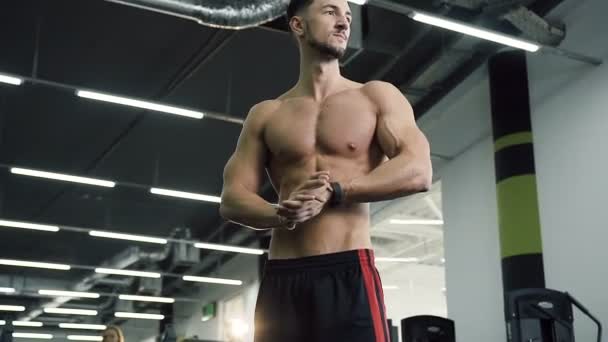 Attractive young man without t-shirt rub his hands on the gym background. - Felvétel, videó