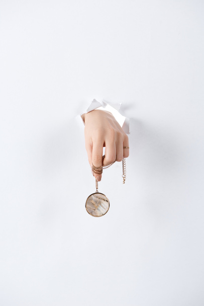 cropped image of woman holding hand with beautiful luxury round locket with marble through white paper - Фото, изображение