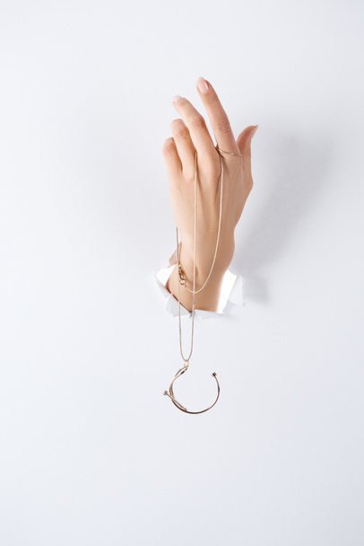 cropped image of woman holding hand with beautiful luxury necklace through white paper - Valokuva, kuva