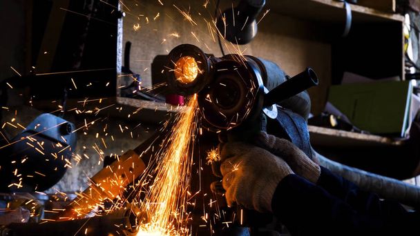 Gros plan d'un ouvrier qui coupe du métal avec une meuleuse. Cadre. Étincelles lors du broyage du fer. Découpes circulaires de disques métalliques
 - Photo, image