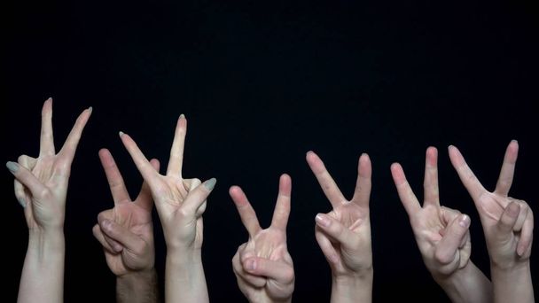 Руки натовпу зі знаком перемоги. Крупним планом багато рук з піднятими кулаками потім змінилися на знак перемоги. Метафора війни і миру
 - Фото, зображення
