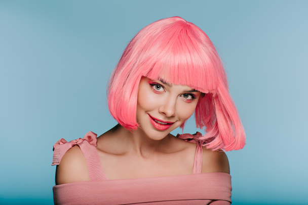 menina sorridente na moda posando em peruca rosa isolado em azul
 - Foto, Imagem