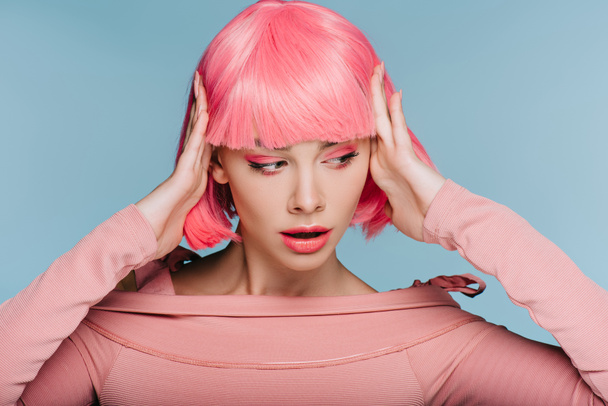 μόδας κορίτσι χειρονομίες και θέτοντας σε ροζ περούκα που απομονώνονται σε μπλε - Φωτογραφία, εικόνα