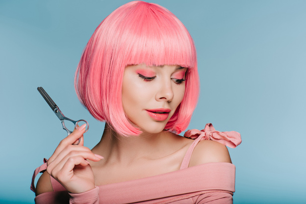 beautiful stylish girl in pink wig holding scissors isolated on blue - Valokuva, kuva