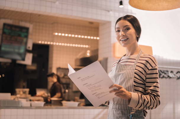 Appealing beautiful woman holding menu of her restaurant - Фото, изображение