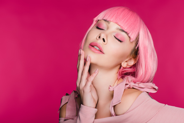 tender stylish young woman in pink wig posing with closed eyes, isolated on pink - Fotó, kép