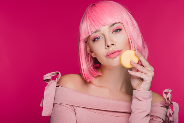 beautiful woman in pink wig posing with macaron isolated on pink - Photo, Image