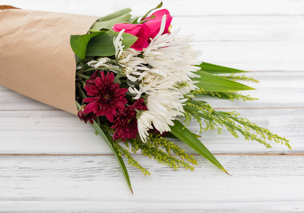 Beau bouquet de roses, oeillet blanc et fleurs de chrysanthème rouge sur fond de bois blanc
 - Photo, image