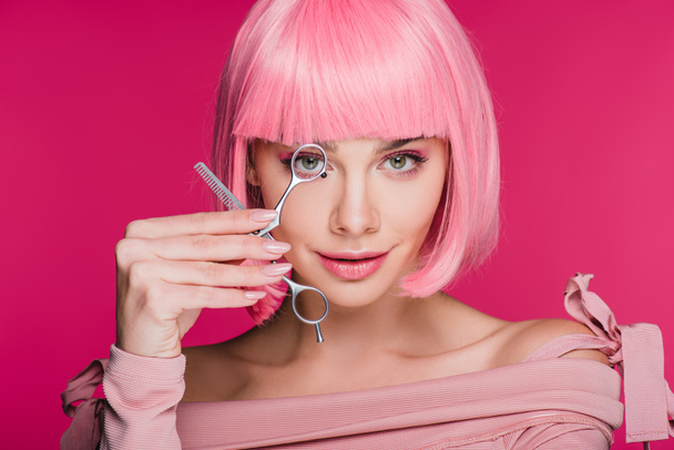 sensual girl with pink hairstyle looking through scissors isolated on pink - Photo, Image