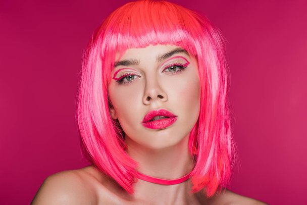 schöne Mädchen mit trendigem Make-up posiert in neonrosa Perücke, isoliert auf rosa - Foto, Bild