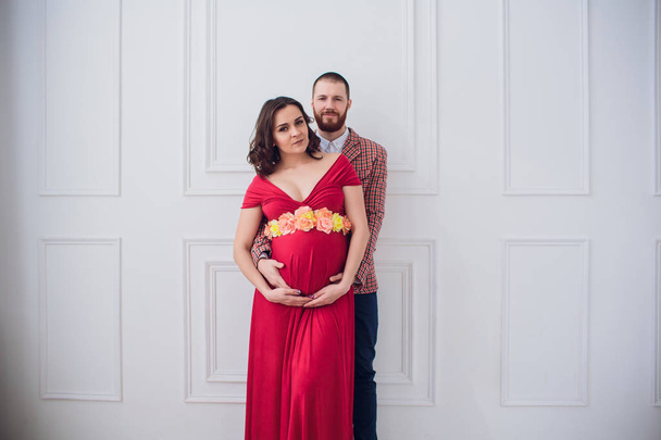 Stylish pregnant couple. pregnant girl in red dress - Φωτογραφία, εικόνα