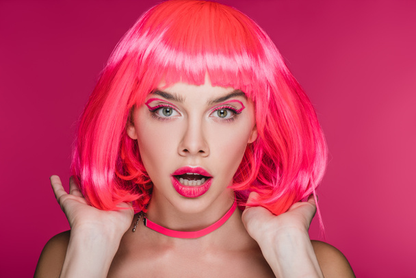 shocked fashionable girl posing in neon pink wig, isolated on pink - Photo, Image