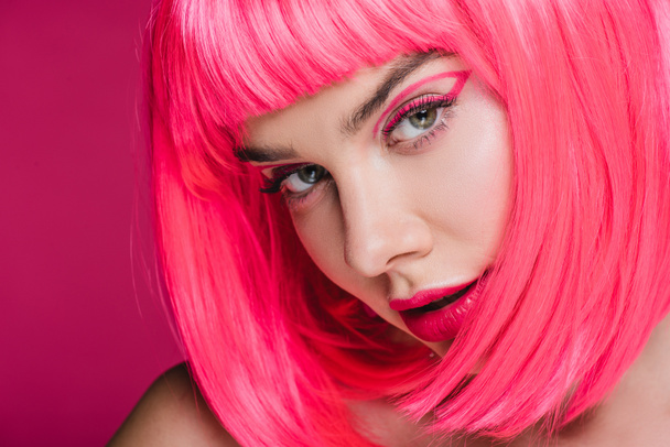 beautiful girl with fashionable makeup posing in neon pink wig, isolated on pink - 写真・画像