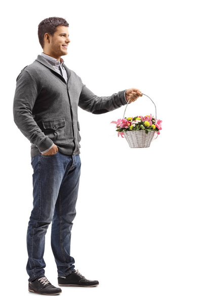 Full length shot of a handsome young man standing with a basket full of flowers isolated on white background - Φωτογραφία, εικόνα
