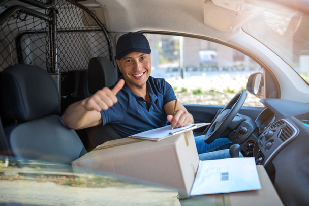 Delivery man sitting in a delivery van - Фото, изображение