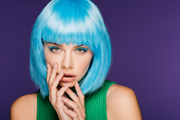 attractive girl posing in blue wig, isolated on purple - Фото, изображение
