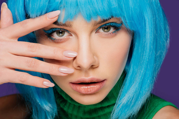 atraktivní dívka s make-upem pózuje v modré paruce, izolované na fialová - Fotografie, Obrázek