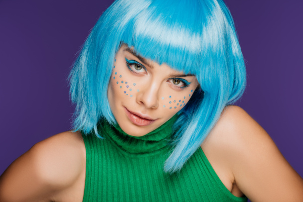 όμορφη νεαρή γυναίκα με μπλε περούκα και τα αστέρια στο πρόσωπό, απομονώνονται σε μωβ - Φωτογραφία, εικόνα