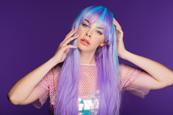 modèle attrayant posant en perruque violette avec des étoiles sur le visage, isolé sur violet
 - Photo, image