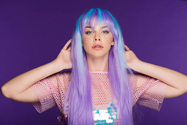 pretty fashionable girl posing in violet wig with stars on face, isolated on purple - Fotografie, Obrázek