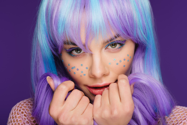 atraktivní smyslná dívka pózuje v fialovou paruku s hvězdami na obličeji, izolované na fialová - Fotografie, Obrázek