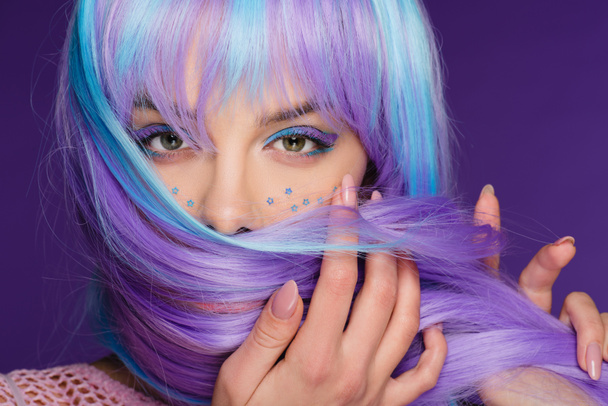 piękna stylowa dziewczyna stwarzających w fioletowe wig z gwiazdami na twarzy, na fioletowym tle - Zdjęcie, obraz