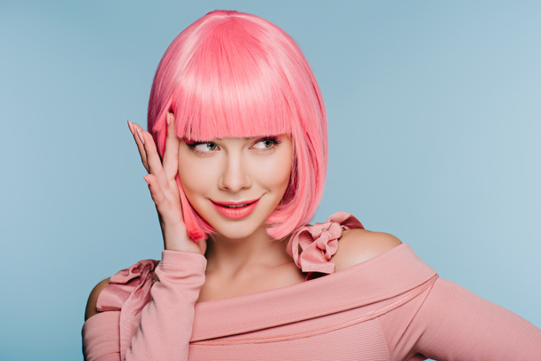 happy fashionable girl gesturing and posing in pink wig isolated on blue - Foto, imagen