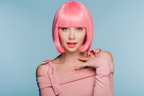 стильная девушка жестикулируя и позируя в розовом парике изолированы на синий
 - Фото, изображение